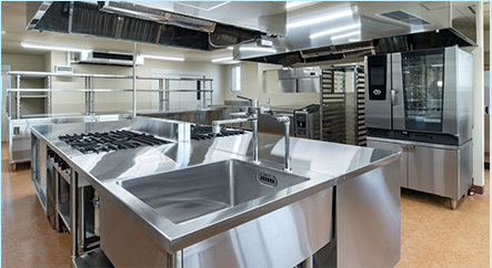 Modern commercial kitchen with stainless steel appliances and equipment.