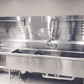 Stainless steel kitchen sink and backsplash in a professional kitchen setting