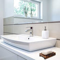 Modern bathroom with a white sink, mirror, and decorative elements.