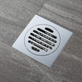 Metal floor drain cover on a gray tiled floor