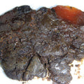 Close-up of a dark brown, craggy rock on a white background