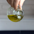 Hand pouring olive oil from a bottle onto a surface