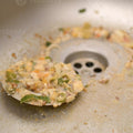 Dirty sink with food scraps and a spoonful of food near the drain