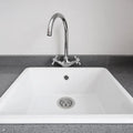 White kitchen sink with silver faucet on a gray countertop