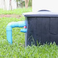 Black water tank with blue pipe on grass